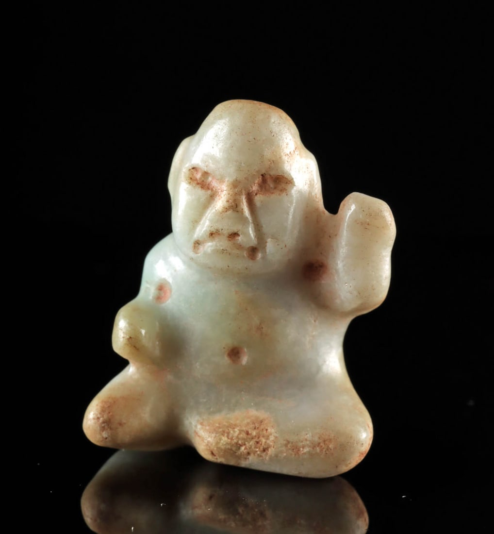 Choice Miniature Olmec Jade Seated Baby Face Figure: Pre-Columbian, Southern Mexico to Guatemala, Olmec, ca. 1200 to 400 BCE. An exquisite jade figure, expertly carved to depict a miniature Olmec "baby" facing forward, seated with one leg bent inward an