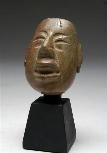 An Olmec Stone WereJaguar Mask, ex-Museum: Pre-Columbian, Olmec Culture, Las Bocas, Mexico, ca. 1500 - 1200 BC, Stone "Werejaguar" mask of anthropomorphic "Baby" Face. Custom museum-quality stand. Head itself measures 2-1/2"H x 2"W. Provenance