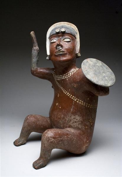 An Exceptional Jalisco Seated Warrior: Pre-Columbian, Jalisco culture, West Mexico, Ca 200 BCE - 200 CE. Finely executed pottery warrior shown seated, possibly knocked down by his enemy, holding axe in right hand and shield in his left, he