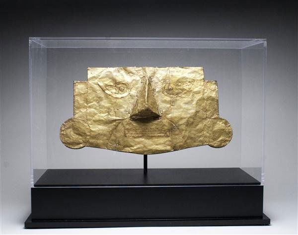A Lambayeque / Sican Gilded Gold Mask: Pre-Columbian, Sican - Chimu Culture, North Coast Peru, ca 800-1000 CE. Gold mask having almond-shaped eyes, nose in high relief, mouth in rectangular incised pattern. Originally attached to a textile