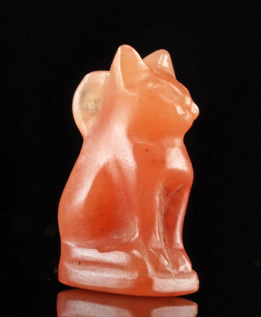 Egyptian Carnelian Cat Amulet of Bastet: Ancient Egypt, Late Dynastic period, ca. 664 to 332 BCE. An adorable hand-carved and hand-drilled carnelian bead is a beautiful vermillion hue with swirls of white inclusions. Seated on its haunches, 