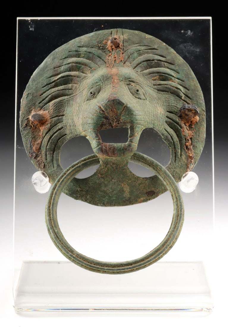 Roman / Byzantine Bronze Lion Ring Pull Handle: Roman, Imperial Period to Byzantine era, ca. 1st to 6th century CE. A cast leaded-bronze ring pull handle in the form of a male lion, featuring a detailed relief snout and incised details, with the ma