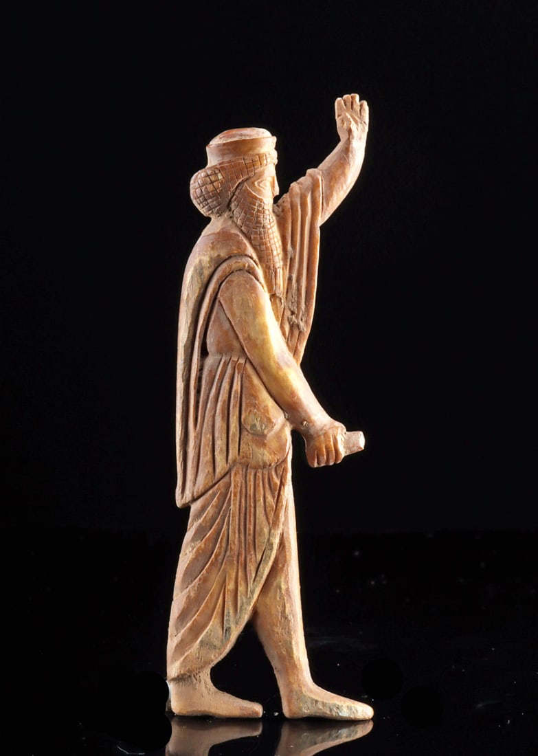 Parthian Bone Plaque of Striding Male Figure: Ancient Near East, Parthian Empire, ca. 247 BCE to 224 CE. A fine bone plaque hand-carved in the form of a draped male figure, perhaps a priest or dignitary, striding right with one hand raised. Crown