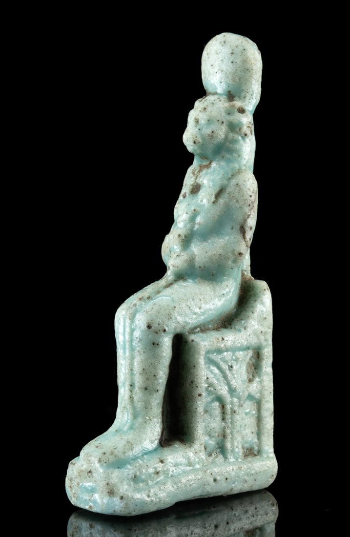 Egyptian Faience Pendant Lion Headed Sekhmet on Throne: Ancient Egypt, Late Dynastic to Ptolemaic Period, ca. 664 to 30 BCE. A mold-made faience amulet depicting Sekhmet, the lioness-headed goddess of war, destruction, and healing, seated upon a throne. Sh