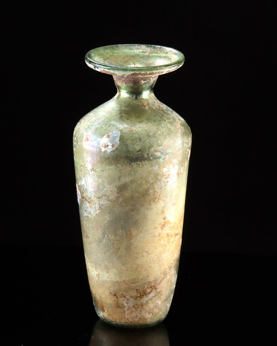 Roman Glass Cylindrical Bottle (Intact!): Roman, Imperial Period, ca. 2nd to 4th century CE. A lovely free-blown, near-translucent glass bottle of a pale-green coloration. The vessel has a slight concave base with a rough pontil, smooth walls