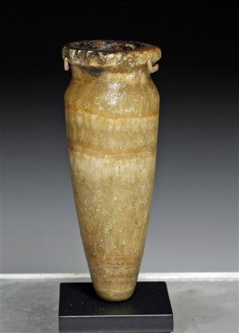 An Egyptian Alabaster Cosmetic Jar: Egypt, Middle Kingdom, Ca. 1985-1773 BCE. A very nice example of a carved alabaster cosmetic container. Cone shaped with slight flared rim. Comes with custom stand. 3-1/2”H. Provenance: Ex-Glenn Woo