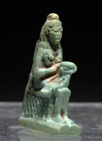 An Egyptian Isis and Horus Faience Amulet: Egypt, Ca 26th Dynasty, Ca. 600 BCE. Small "good luck" charm featuring seated Isis holding an infant Horus; incised detail on bodies and throne. 1-1/2”H x 7/8”L. Provenance: Ex-Glenn Woods Collect
