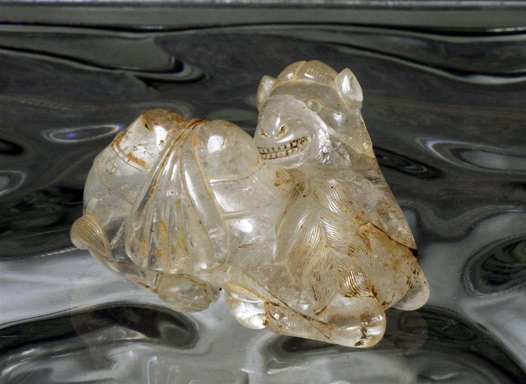 A Chinese Carved Crystal Bactrian Camel: China, Warring States Period, Ca 5th to 3rd century BCE. Carved camel from a single piece of clear quartz crystal, showing remarkable detail. Head turned right, fur incised on front and tail, bag drap