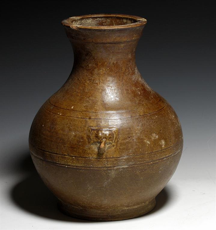 A Han Dynasty Brown Glazed Jar: China, Han Dynasty, Ca 220 BCE to 200 CE. Lovely brown-glazed pottery jar of bulbous form, slightly flared neck and rim, each side decorated with impressed Tao Masks. Entire vessel covered in medium b