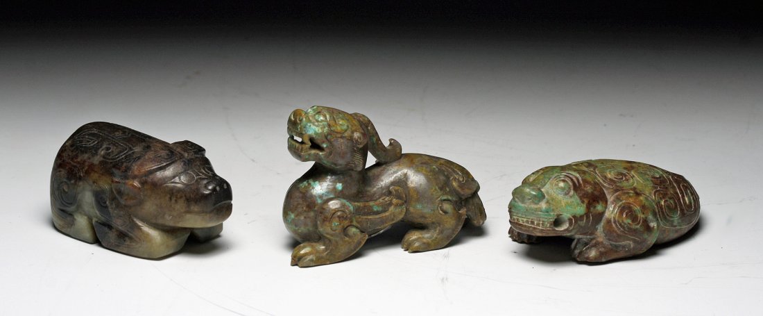 A Set of Three Chinese Han Dynasty Stone Beasts: China, Han Dynasty, Ca 220 BCE to 200 CE. Set of three carved stone creatures, each carved in great detail. First, standing dragon with toothy grin. Next a water buffalo, horns in deep relief, incised