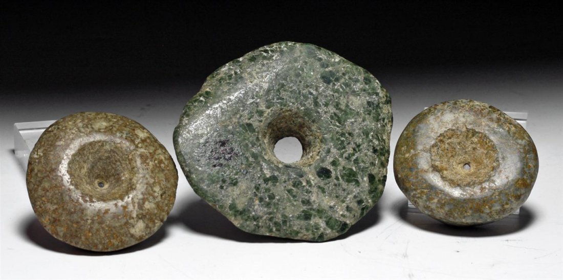 Three Pre-Columbian Stone Ear Spools: Guerrero / Mezcala, Mexico, ca 800 to 500 BCE. Set of three stone earspools. First, matching pair of brown stone spools, each with shallow depression, small hole in center. Next, green speckled stone 