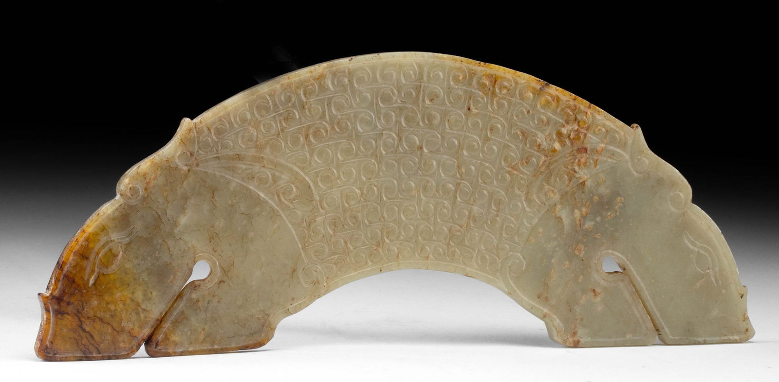 Ancient Zhou Dynasty Jade Huang Pendant, Zoomorphic Terminals: East Asia, China, Western Zhou Dynasty, ca. 1050 to 771 BCE. A fabulous nephrite jade huang disk segment boasting mottled hues of celadon and forest green, reds and, and mocha. Featuring a pair of dri