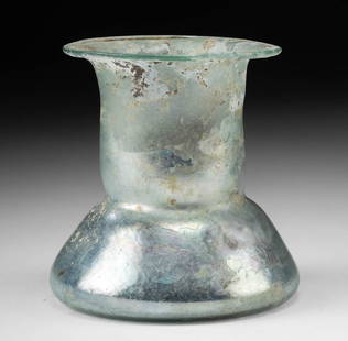 Roman Glass Wide Unguentarium - Metallic Iridescence: Roman, Imperial Period, Holy Land, ca. 1st to 3rd century CE. A dazzling glass jar or unguentarium of a thick 'candlestick' form, skillfully blown from thin glass in a translucent light blue-green hue