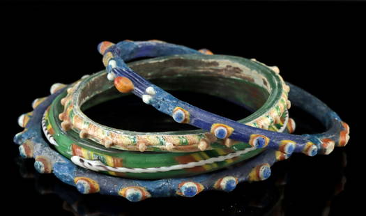 Four Roman to Byzantine Glass Bracelets: Roman, late empire, to Byzantine, ca. 5th to 7th century CE. A lovely group of 4 glass bracelets, each of circular form in sizes ranging from child to woman's. Two of the bracelets are of blue glass,