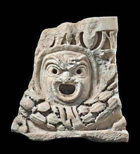 Roman Marble Architectural Relief w/ Actor's Mask: Roman Empire, ca. 1st to 2nd century CE. A compelling fragment of a Roman marble relief carved in high relief with a striking tragic theater mask, its features exaggerated for dramatic effect: arched