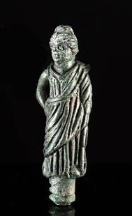 Roman Leaded Bronze Votive of a Woman: Roman, Imperial period, ca. 1st to 3rd century CE. A delightful leaded bronze votive figure of a woman, perhaps a goddess, standing with one hand on her hip and the other at her side. Billowing folds