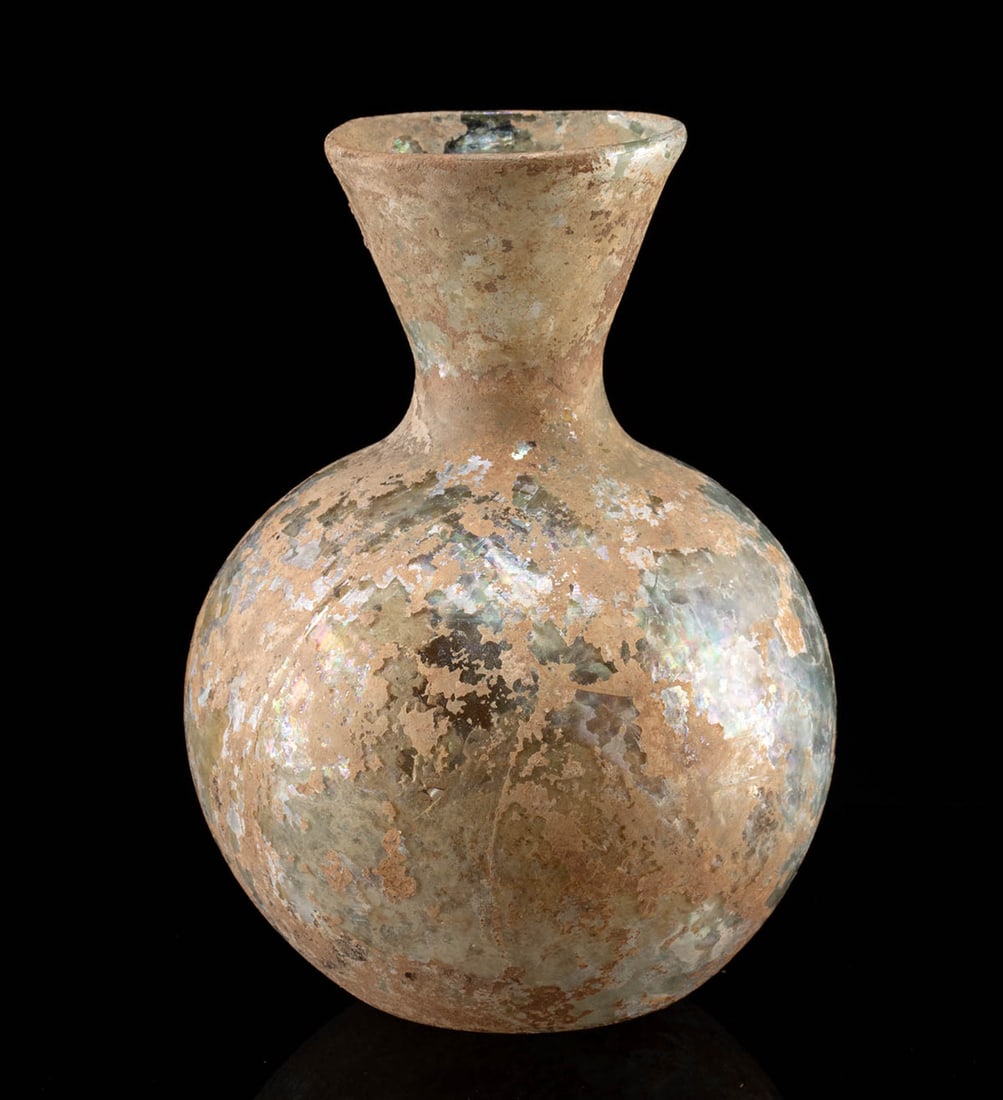 Roman Glass Flask: Roman, Imperial period, ca. 1st to 3rd century CE. A beautifully free-blown glass jar of translucent light blue presents an elegant form: a globular body rising to an attenuated neck and flared spout,