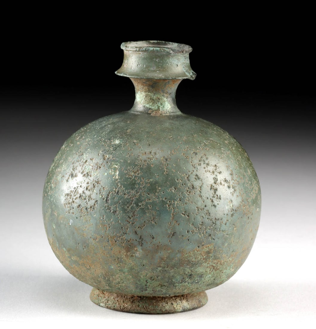 Ancient Roman Bronze Aryballos Toiletry Flask: Rome, Imperial Period, ca. 1st to 2nd century CE. A cast bronze aryballos of harmonious and rounded form, its surface gently weathered to a soft green patina. The vessel features a nearly spherical bo