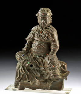 Chinese Ming Bronze Statue of Deified General Guan Yu: East Asia, China, Ming Dynasty, ca. 16th to 17th century CE. A cast bronze statue of Guandi, seated on an animal skin draped over a pedestal, wearing armor adorned with the characteristic mountain pat