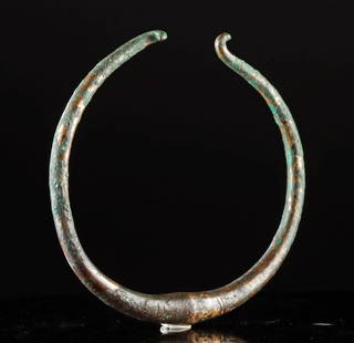 Ancient Iran Luristan Bronze Torque Necklace: Near East, Northwestern Iran, Luristan culture, ca. 1200 to 800 BCE. A cast bronze torque (torc) formed from a single rod with gracefully tapering terminals, the ends curling inward into hooks. The th