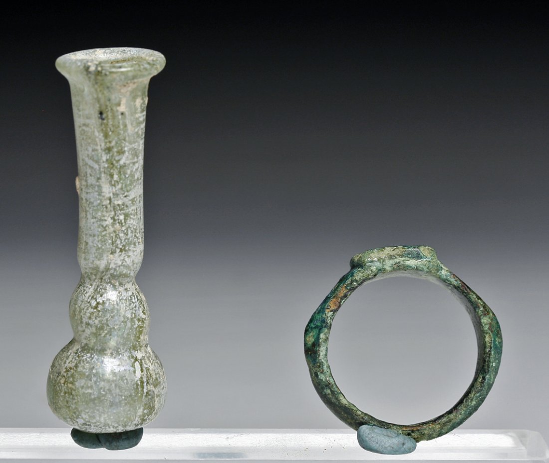 Miniature Roman Glass Jar + Roman Bronze Ring: Rome, Ca. 1st-2nd Century CE. A miniature roman glass vase of greenish blue tinge, composed of a stacked spherical base, with a cylindrical neck that tapers out at the end. The Roman ring has an inter