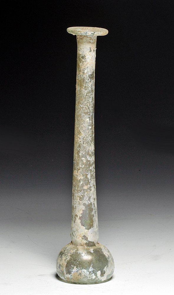 A Roman Glass Candlestick Unguent: From ancient Rome, ca. 2nd century AD, most likely from Syria or Lebanon (glass centers of the Roman Empire). Tall glass unguent in light green glass, bulbous base, very long neck and widened rim, now