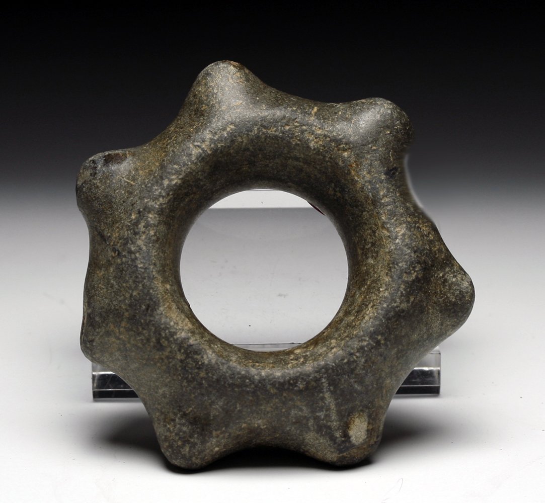 Pre-Columbian Chavin Miniature Stone Mace Head: Northern Peru, Chavin, Ca 1100 to 500 BCE. Small carved stone mace head, certainly ceremonial in nature due to its size, with 7 extending nodes and large central shaft hole. 2-5/8" W. PROVENANCE Ex-Br