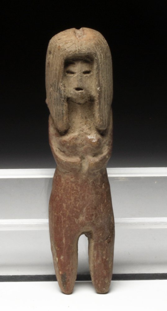 A Validivan Pre-Columbian Venus Figure: Ecuador, Ca 2000 BCE. Pottery solid molded figure of a standing female, long straight hairdo, arms to her belly, simple impressed facial features, remains of original red pigment. 3-5/8" H. PROVENANCE