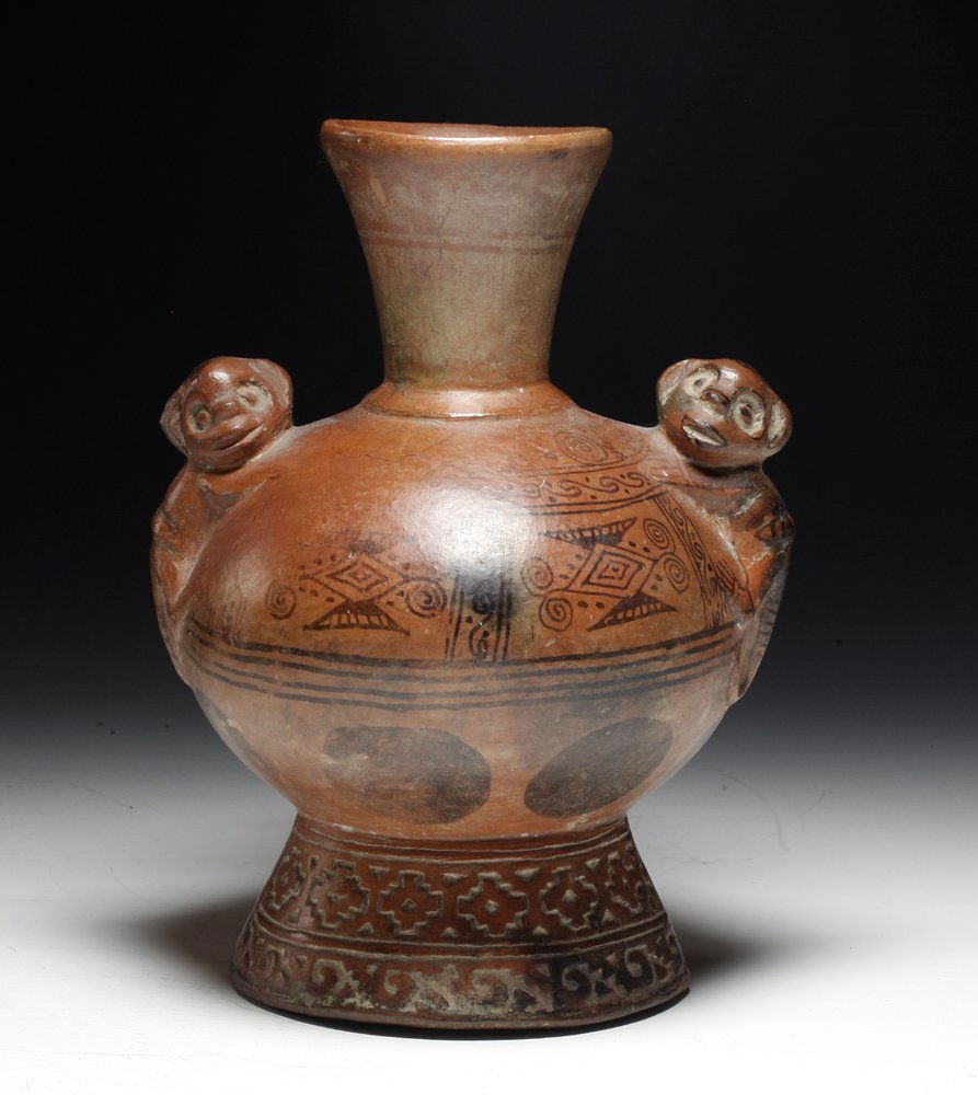 Cute Pre-Columbian Lambayeque Pottery Jar: Northern Peru, Ca 800 to 1100 CE. Lovely redware pottery jar with twin monkeys perched atop the shoulders, very elaborate cross and scroll carved base, flaring spout and strap handle. Jar painted with