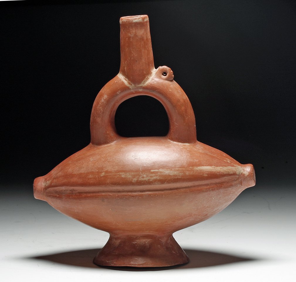 Chimu Redware Fruit-Form Stirrup Jar: Pre-columbian, Northern Peru, Ca 1200 to 1475 CE. Melon-shaped redware pottery jar, possibly representing a cacao pod with stirrup spout enraging from the top, carved decoration on base. 7-1/2"H. PRO