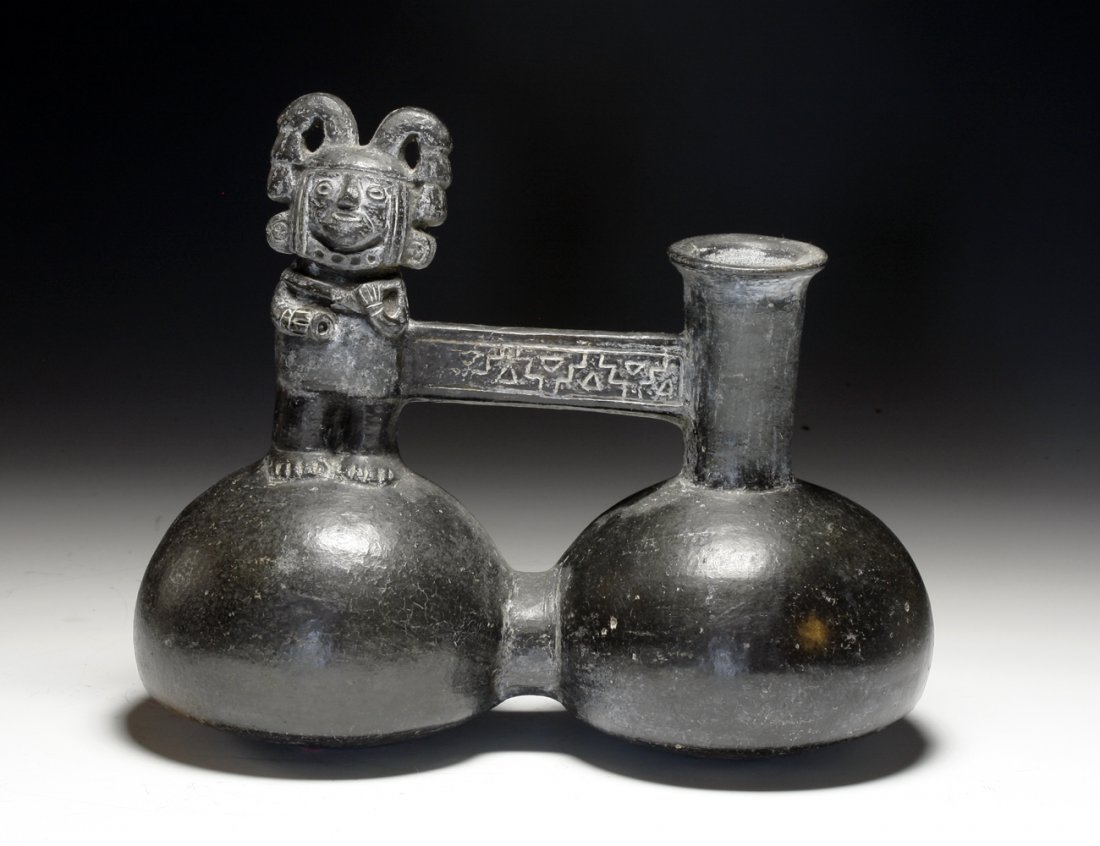 Inca Blackware Bridge-Spouted Jar: Pre-Columbian, Peru, Ca 1400 to 1500 CE. Double-lobed blackware pottery vessel with standing lord upon one globe, chimney spout atop other and incised bridge connecting. 6-3/4" H. PROVENANCE: EX- Mary