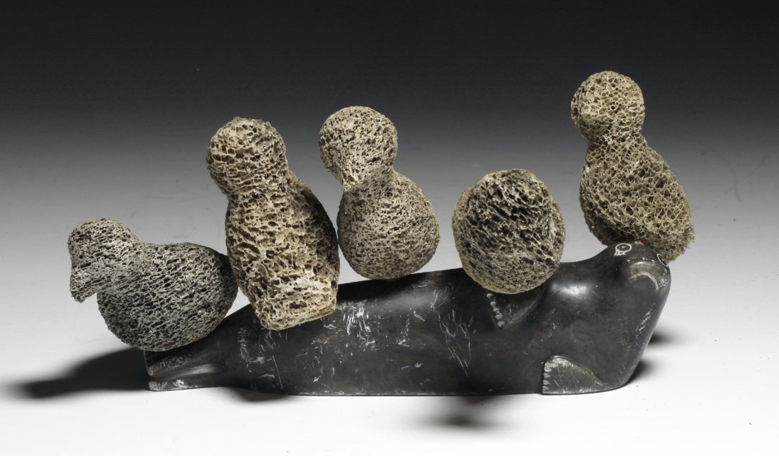 Delightful Eskimo Soapstone Carving of Seal and Birds: Canada, Northern Territories, Ca 1940 to 1950. A very sweet carving of a sprawled out seal/sea lion on which sits 5 bone carved birds, each attached with wooden peg. Seal measures 7" L. PROVENANCE: EX