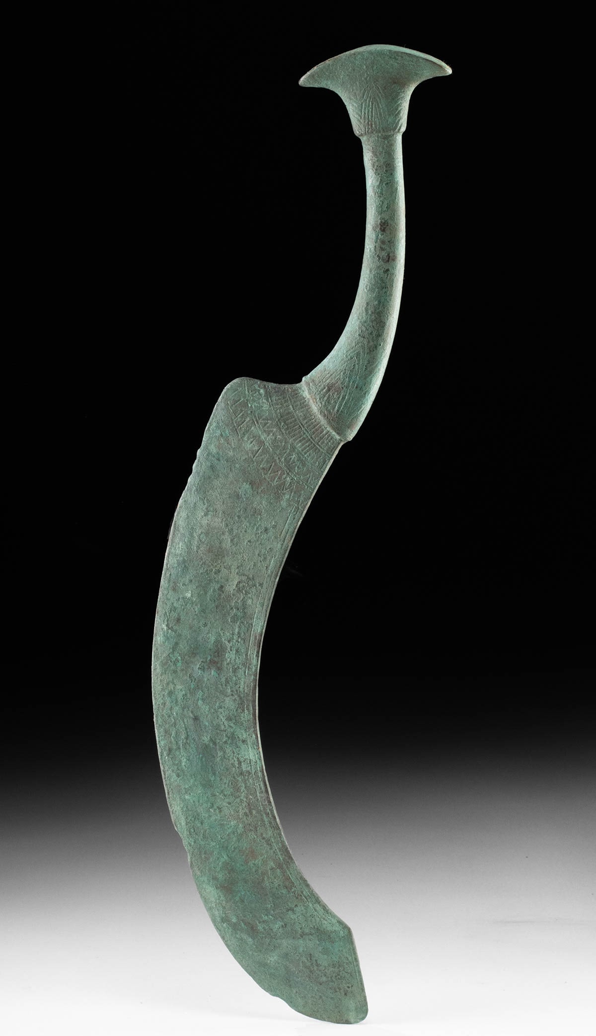 Rare Egyptian Bronze Embalmer’s Knife with Lotus Finial: **Originally Listed At $2000** Egypt, New Kingdom, Ramesside Period, ca. 1292 to 1070 BCE. A remarkably rare Egyptian bronze embalmer's knife, its crescentic blade and elegantly curving handle forming