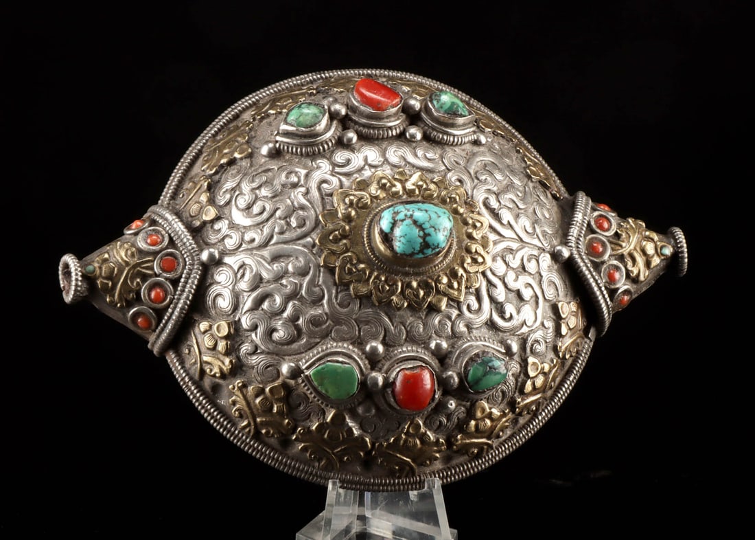 Tibetan Silver Hair Ornament, Turquoise & Coral Inlays: Central Asia, Tibet, ca. late 19th to early 20th century CE. A striking silver hair ornament of domed form, chased with intricate scrolling motifs and decorated in relief with applied silver-copper fl