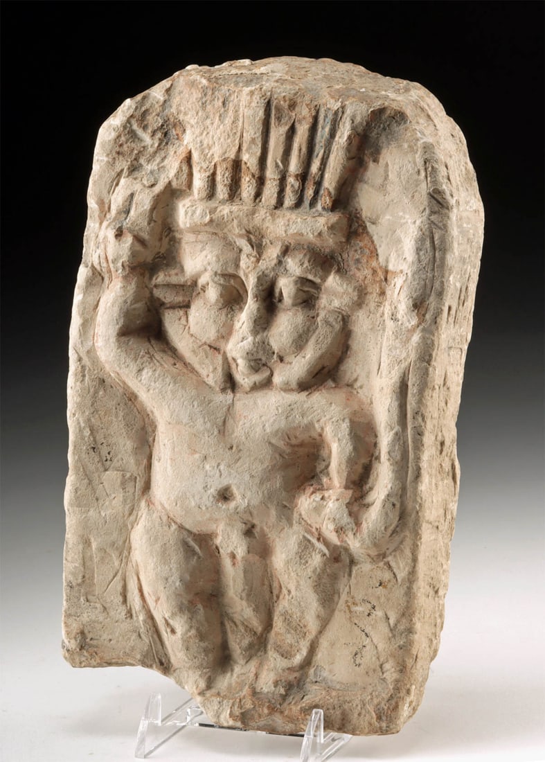 Ptolemaic Limestone Relief of Bes, God of Household Protection: Egypt, Ptolemaic Period, ca. 305 to 30 BCE. A lively limestone relief depicting Bes, the dwarf god of protection, fertility, and household joy in ancient Egypt. The squat yet commanding figure is show