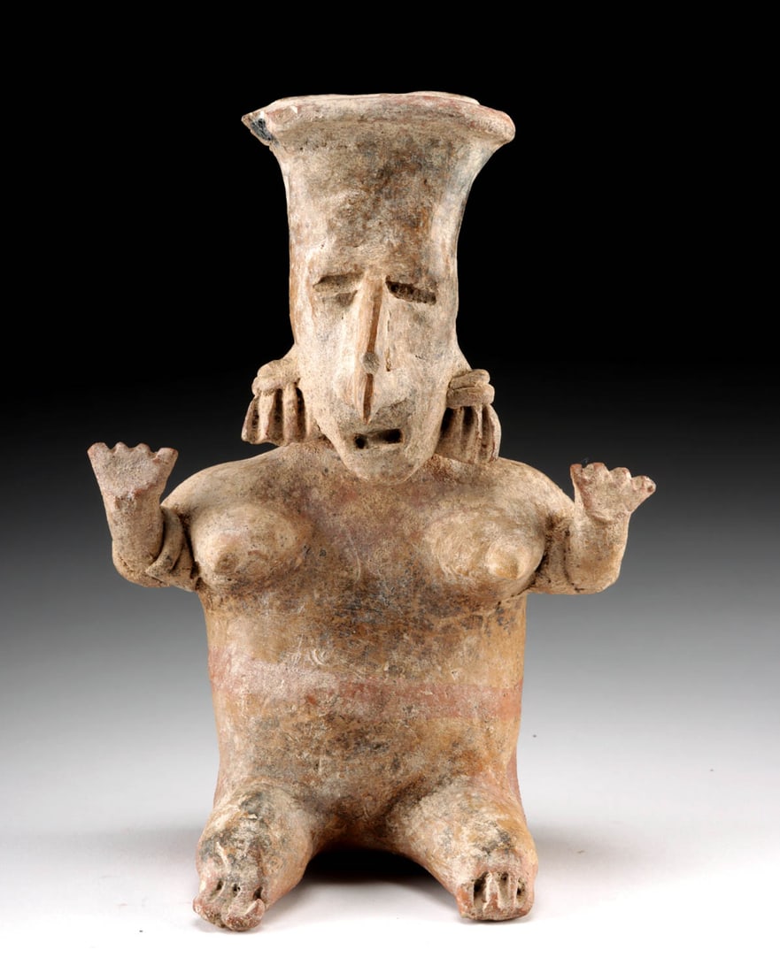 Jalisco Pottery Seated Nude Female Figure: Pre-Columbian, West Mexico, Jalisco, ca. 300 BCE to 300 CE. A compelling hollow pottery figure of a nude seated woman from ancient Jalisco, her arms lifted in a gesture evocative of astonishment or di