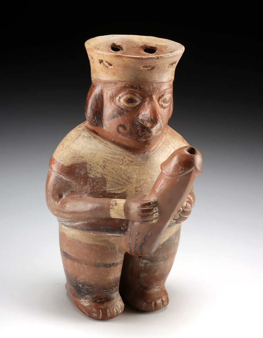 Moche Pottery Dribble Cup - Warrior w/ Huge Phallus: Pre-Columbian, north coast Peru, Moche, Phase 3, ca. 350 to 500 CE. An evocative pottery drinking vessel boasting a striking form: a standing warrior who boldly grasps his prominent phallus with both