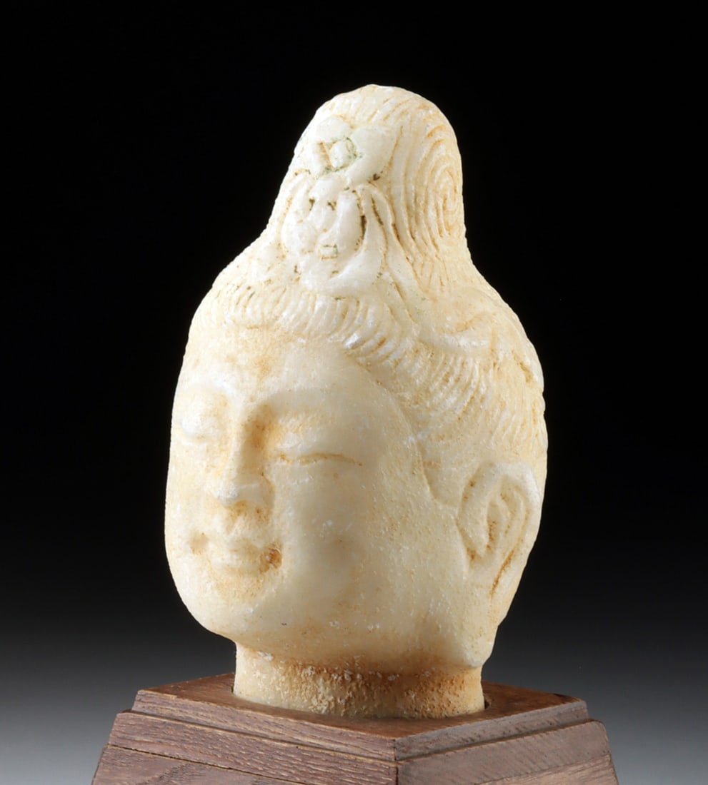 Qing Marble Head of Guanyin (Bodhisattva of Mercy): East Asia, China, Qing Dynasty, ca. 19th century CE. A serene and quietly luminous marble head of Guanyin, carved with a softness that seems to slow the breath. The face is full and gently rounded, th