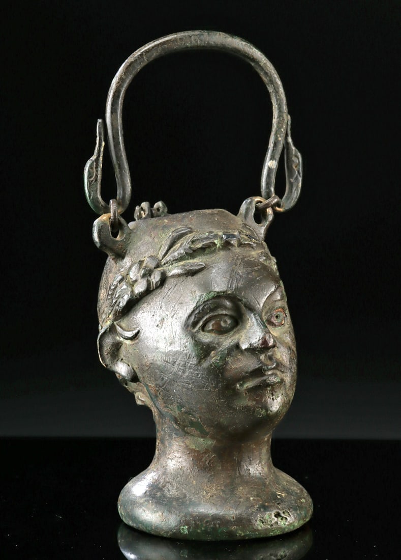 Roman Bronze Balsamarium of Nobleman, ex-Sotheby's: Roman, Imperial Period, ca. 1st to 3rd century CE. A finely cast Roman bronze Balsamarium, sculpted in the form of a youthful male head, possibly representing Dionysus (Bacchus) or a victorious youth,