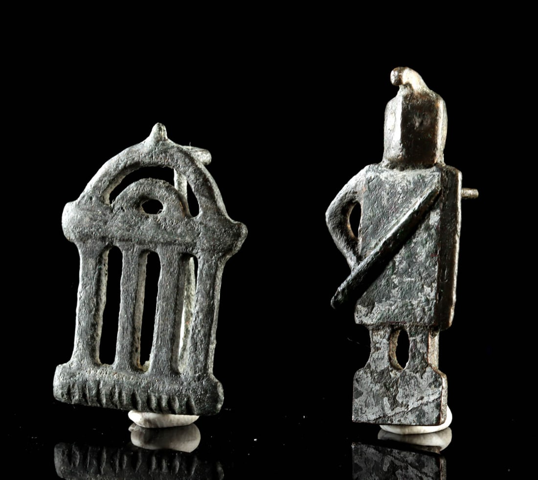 Two Roman Copper Alloy Fibulae - Gladiator and Temple: Roman, Imperial period, ca. 1st to 3rd century CE. A matched pair of Roman copper alloy fibulae, one cast in the form of a temple facade and the other as a standing gladiator, captures the breadth of