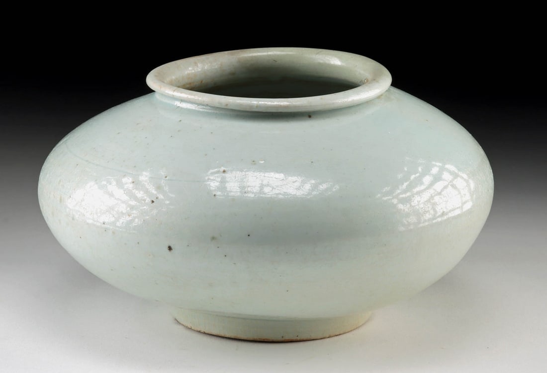 18th C. Korean Joseon Dynasty Celadon Glazed Jar: East Asia, Korea, Joseon Dynasty, ca. 18th to 19th century CE. A luminous porcelain jar glazed in soft celadon tones, embodying the restrained elegance characteristic of late Joseon ceramics. The vess