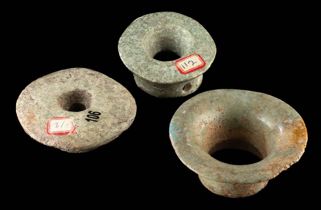 Three Large Ancient Maya Jadeite Ear Spools: Pre-Columbian, Southern Mexico to Guatemala, Maya culture, ca. 500 to 900 CE. A group of three hand-carved jadeite ear spools, each shaped with a wide flaring rim and hollow cylindrical body. Two of t