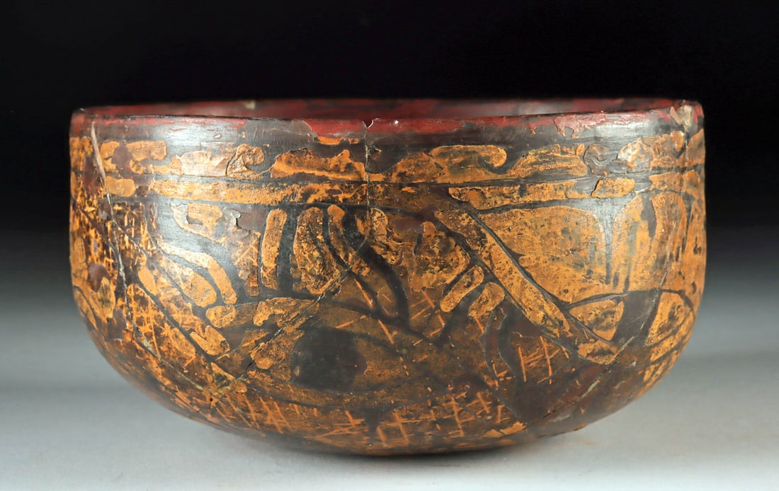 Incised Nazca Abstract Polychrome Pottery Bowl: Pre-Columbian, Peru, Paracas to Nazca, ca. 100 BCE to 800 CE. A pottery bowl with a dark ground, encircled by incised abstract designs, where eye-like motifs nestle within flowing curvilinear bands hi