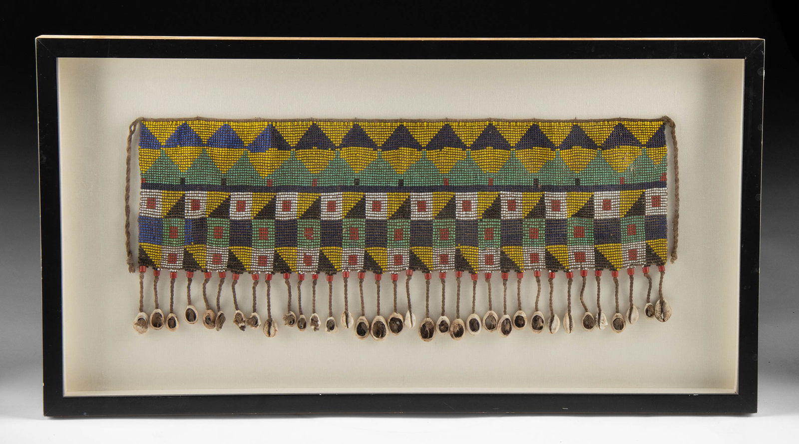 Framed African Kirdi Beaded Modesty Apron Cowrie Fringe: West Africa, Cameroon, Bana Guili (Kirdi) peoples, ca. early to mid-20th century CE. A vibrant beaded modesty apron (dibul kouana), composed of multicolored glass seed beads strung on cotton fiber, wi
