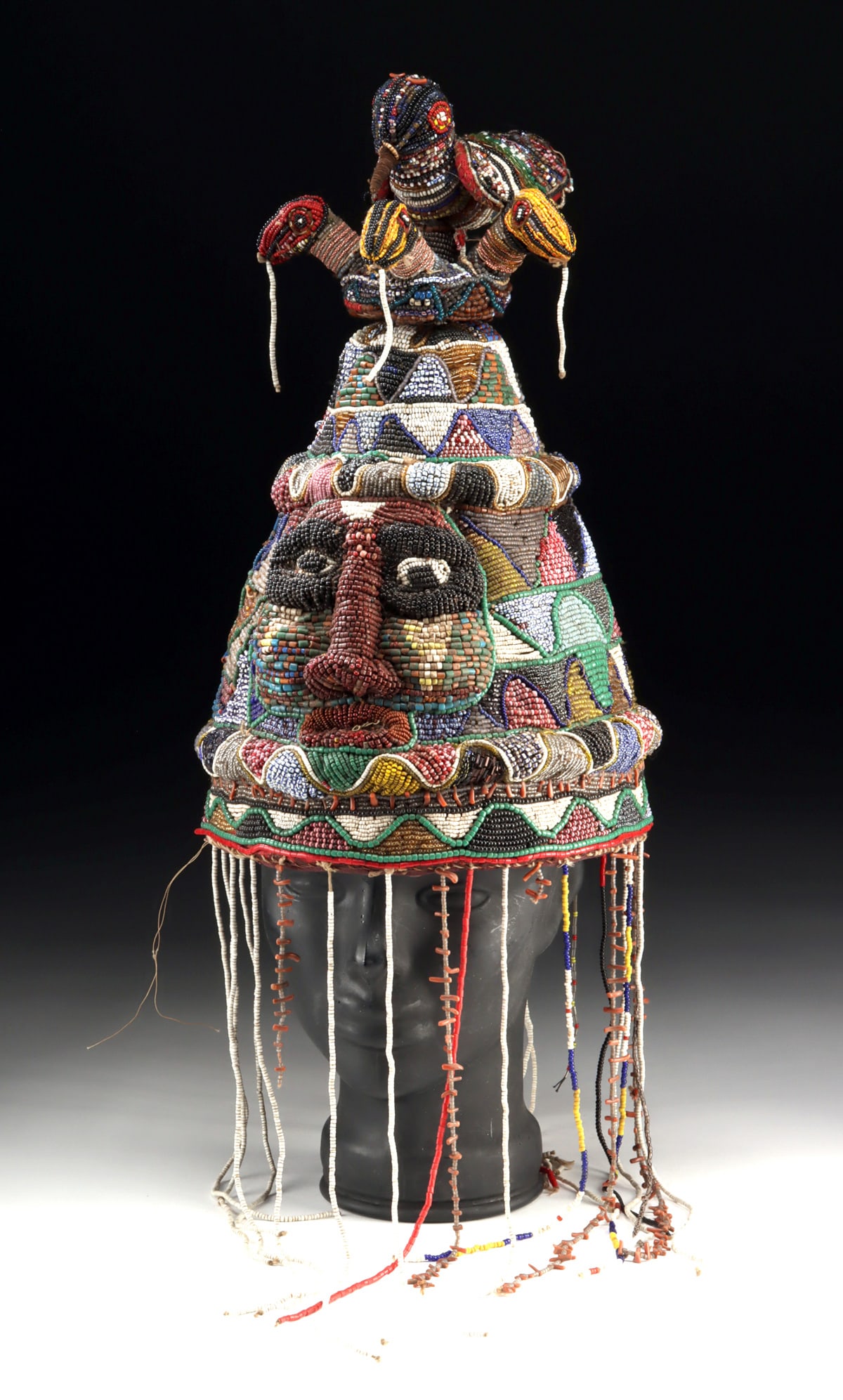 Nigerian Yoruba Beaded Royalty Oba Crown, Snakes & Bird: West Africa, Nigeria, Yoruba, ca. early to mid-20th century CE. A beaded crown (ade) made for a Yoruba oba (king), formed in a classic conical shape with a removable finial surmounted by snakes and a