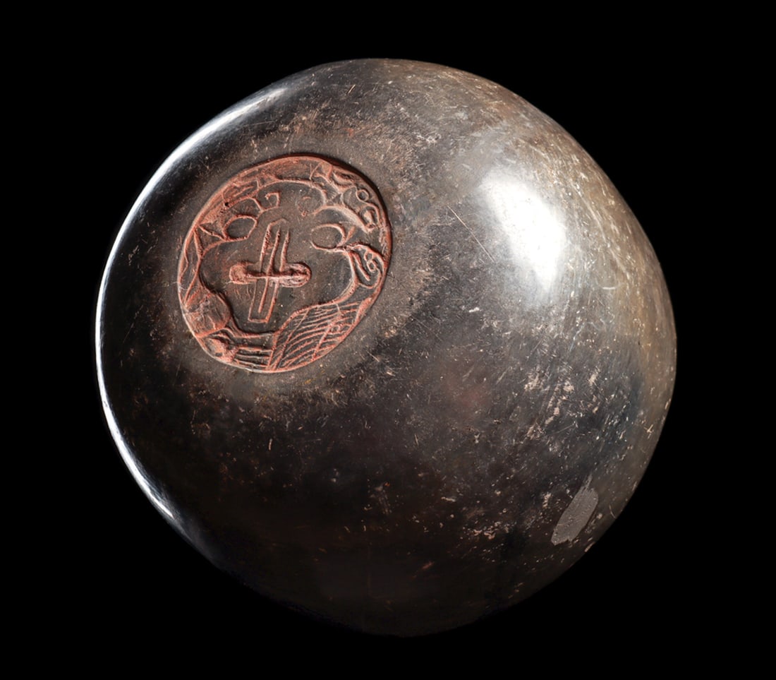 Olmec Grayware Bowl with Carved Roundel: Grayware pottery bowl decorated on the underside with a carved roundel depicting a stylized central feline head with a deer on top of his head and a bird on the lower left. All with cinnabar highlight