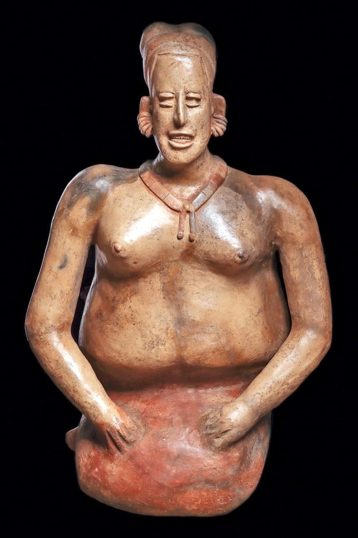 Monumental Jalisco Seated Female Figure: Exceptionally large red-orange and tan color pottery seated female, holding both hands on her lap, wearing a red-orange painted skirt, segmented necklace, multi-ring earrings and a wrapped headdress.