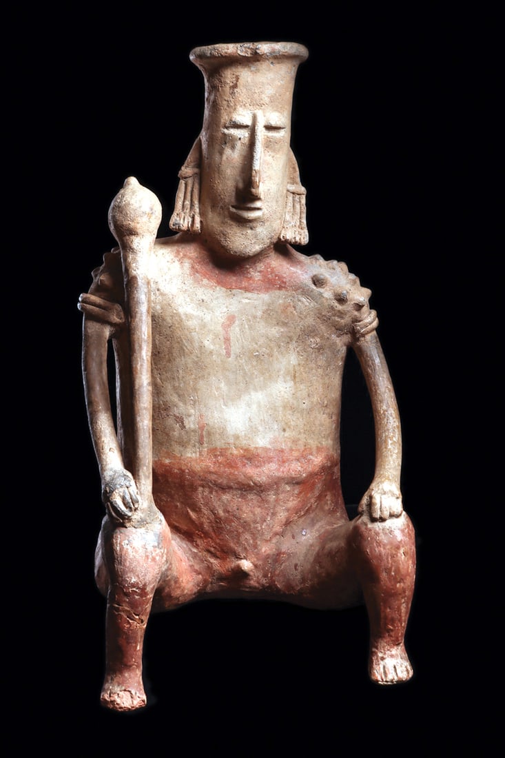San Juanito Seated Figure Holding Club: Large tan and red-brown pottery seated male figure with an elongated head, simple facial features and large angular nose. He rests his hands on his raised knees, holds a long club resting on his right
