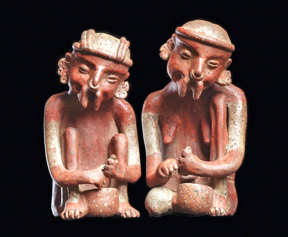 Ixtlan del Rio Pair of Corn Shuckers Figures: Orangeware pottery matching seated, male and female elderly couple, depicted singing and having flanged mouths. Both are looking downwards and holding an ear of corn above a food bowl. White painted
