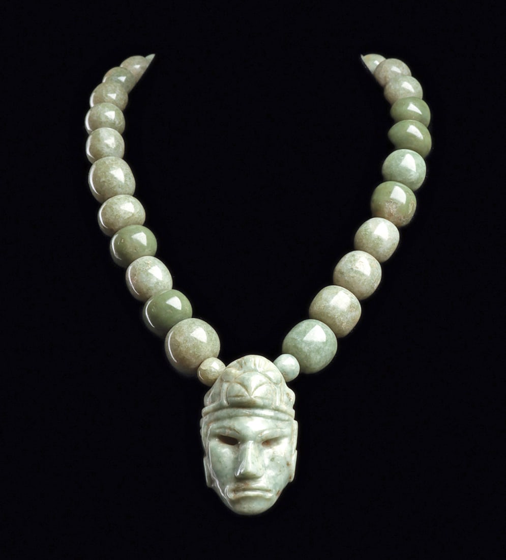 Maya Jade Beaded Necklace with Head Pendant: Single strand pendant necklace composed of thirty-two graduated blue-green jade ball beads with a large center jade pendant depicting the head of a chief, wearing an avian head headdress, having a lar